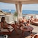 Group of 4 adults in bathing suits relaxing in a private cabana with lounge chairs and ocean views